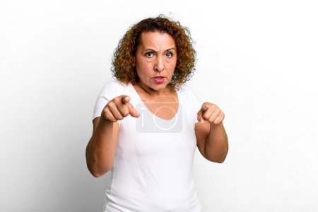 Photo for Middle age hispanic woman pointing forward at camera with both fingers and angry expression, telling you to do your duty - Royalty Free Image