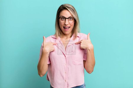 Photo for Blonde adult woman feeling happy, surprised and proud, pointing to self with an excited, amazed look - Royalty Free Image