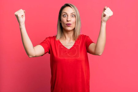 Photo for Blonde adult woman celebrating an unbelievable success like a winner, looking excited and happy saying take that! - Royalty Free Image