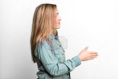 Foto de Blonde adult woman smiling, greeting you and offering a hand shake to close a successful deal, cooperation concept - Imagen libre de derechos