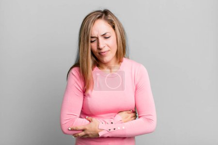 Photo for Blonde adult woman feeling anxious, ill, sick and unhappy, suffering a painful stomach ache or flu - Royalty Free Image