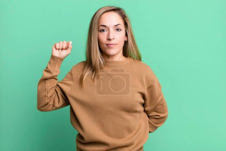 Photo for Blonde adult woman feeling serious, strong and rebellious, raising fist up, protesting or fighting for revolution - Royalty Free Image
