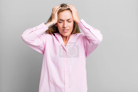 Photo for Blonde adult woman feeling stressed and frustrated, raising hands to head, feeling tired, unhappy and with migraine - Royalty Free Image