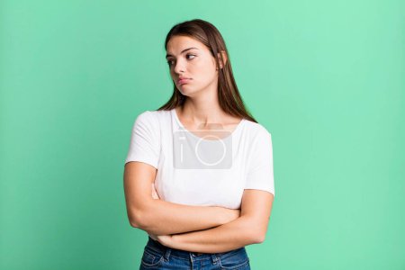 Foto de Pretty young adult woman feeling sad, upset or angry and looking to the side with a negative attitude, frowning in disagreement - Imagen libre de derechos
