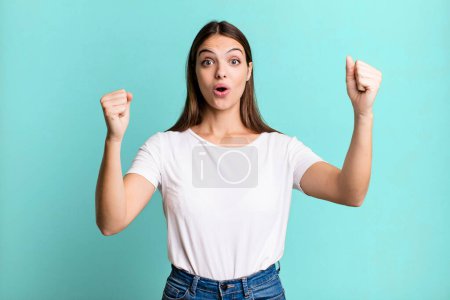 Foto de Pretty young adult woman celebrating an unbelievable success like a winner, looking excited and happy saying take that! - Imagen libre de derechos