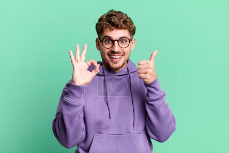 Photo for Young adult caucasian man feeling happy, amazed, satisfied and surprised, showing okay and thumbs up gestures, smiling - Royalty Free Image