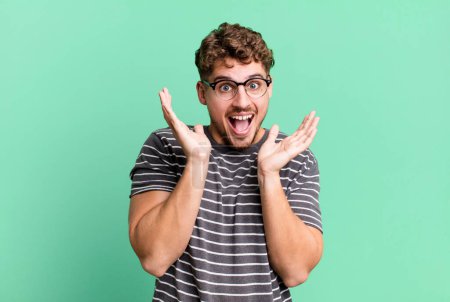 Foto de Young adult caucasian man feeling shocked and excited, laughing, amazed and happy because of an unexpected surprise - Imagen libre de derechos
