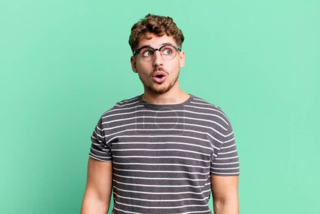Photo for Young adult caucasian man feeling shocked, happy, amazed and surprised, looking to the side with open mouth - Royalty Free Image