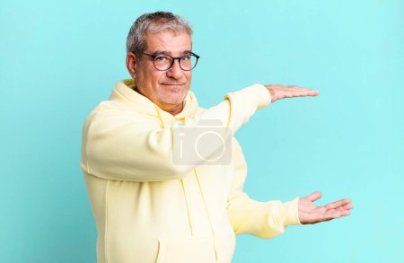 Photo for Middle age senior man smiling, feeling happy, positive and satisfied, holding or showing object or concept on copy space - Royalty Free Image