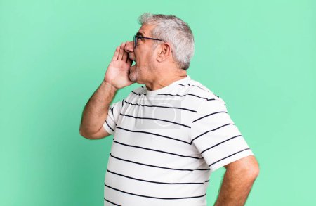 Foto de Hombre mayor de mediana edad vista de perfil, mirando feliz y emocionado, gritando y llamando para copiar el espacio en el lado - Imagen libre de derechos