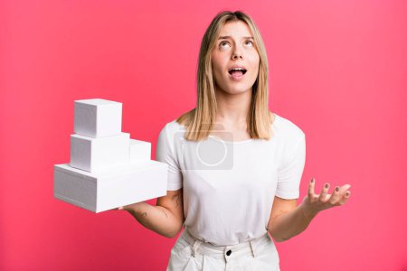 Photo for Young pretty woman looking desperate, frustrated and stressed. blank white boxes concept - Royalty Free Image