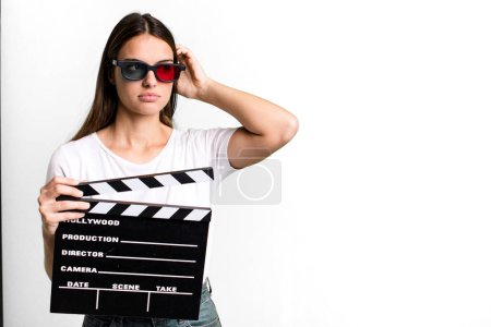 Photo for Young pretty woman feeling puzzled and confused, scratching head. cinema film or movie concept - Royalty Free Image