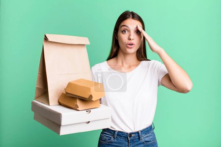 Photo for Young pretty woman looking happy, astonished and surprised. delivery and take away concept - Royalty Free Image