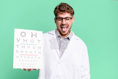 Photo for Young adult caucasian man with cheerful and rebellious attitude, joking and sticking tongue out. optical vision test concept - Royalty Free Image
