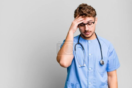 Téléchargez les photos : Young adult caucasian man feeling bored, frustrated and sleepy after a tiresome. nurse concept - en image libre de droit