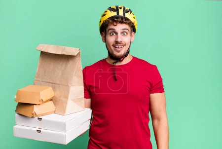 Téléchargez les photos : Young adult caucasian man looking happy and pleasantly surprised.  take away fast food deliveryman concept - en image libre de droit