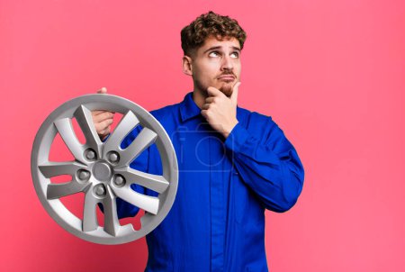 Foto de Young adult caucasian man thinking, feeling doubtful and confused. car repairman or mechanic concept - Imagen libre de derechos