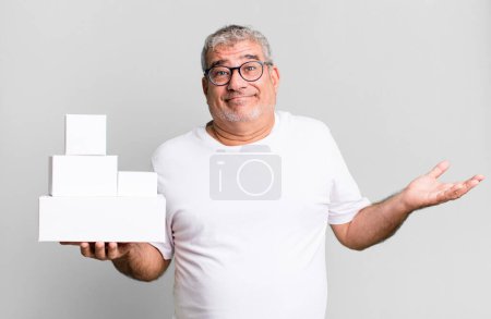 Foto de Hombre mayor de mediana edad sintiéndose desconcertado y confundido y dudando. cajas en blanco de diferentes paquetes - Imagen libre de derechos