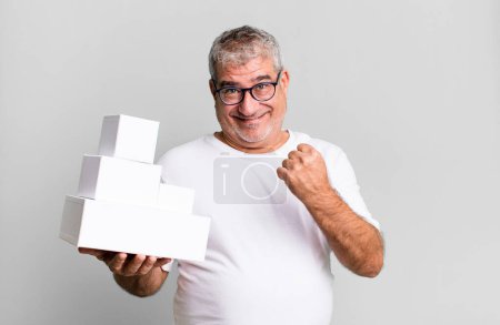 Foto de Hombre mayor de mediana edad sintiéndose feliz y enfrentándose a un desafío o celebración. cajas en blanco de diferentes paquetes - Imagen libre de derechos