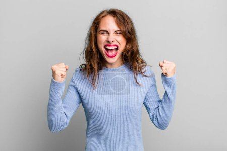 Photo for Young pretty woman feeling happy, positive and successful, celebrating victory, achievements or good luck - Royalty Free Image