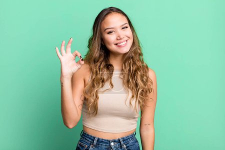 Photo for Young pretty woman feeling happy, relaxed and satisfied, showing approval with okay gesture, smiling - Royalty Free Image