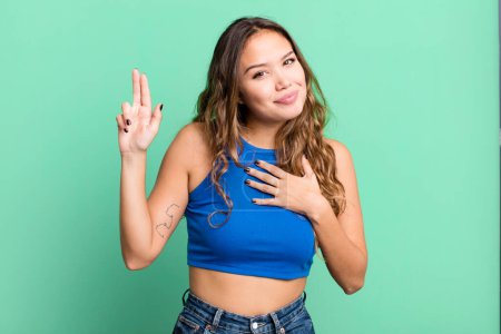 Photo for Young pretty woman looking happy, confident and trustworthy, smiling and showing victory sign, with a positive attitude - Royalty Free Image