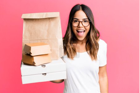 Photo for Hispanic pretty woman looking happy and pleasantly surprised. delivery and take away fast food concept - Royalty Free Image