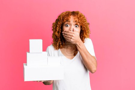 Photo for Red hair pretty woman covering mouth with hands with a shocked. blank packages boxes concept - Royalty Free Image