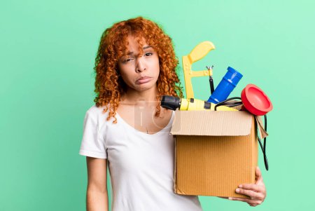 Foto de Red hair pretty woman feeling sad and whiney with an unhappy look and crying. housekeeper and toolbox concept - Imagen libre de derechos