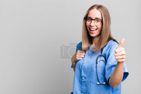 Téléchargez les photos : Se sentant fier, souriant positivement avec les pouces levés. concept d'infirmière - en image libre de droit