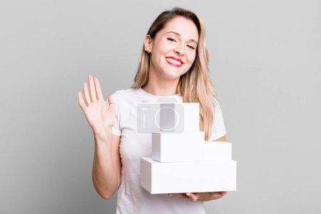 Foto de Sonriendo alegremente, saludándote con la mano, dándote la bienvenida y saludándote. concepto de cajas blancas - Imagen libre de derechos