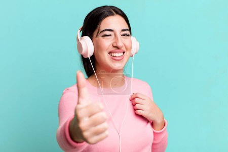 Téléchargez les photos : Feeling proud,smiling positively with thumbs up. listening music with headphones - en image libre de droit