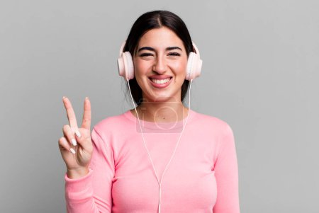 Téléchargez les photos : Smiling and looking friendly, showing number two. listening music with headphones - en image libre de droit