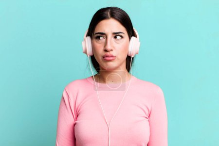 Photo for Feeling sad, upset or angry and looking to the side. listening music with headphones - Royalty Free Image