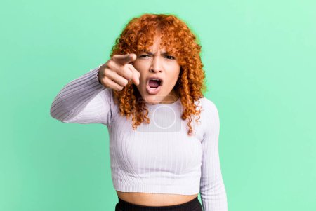 Photo for Redhair pretty woman pointing at camera with an angry aggressive expression looking like a furious, crazy boss - Royalty Free Image