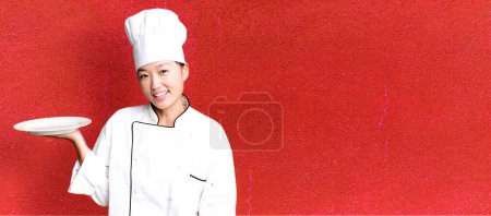 Photo for Young adult pretty asian woman. restaurant chef holding an empty dish - Royalty Free Image