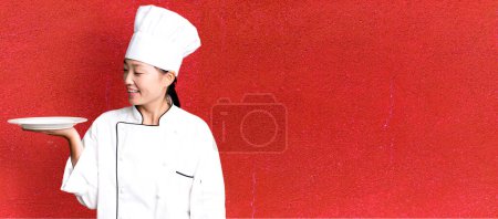 Photo for Young adult pretty asian woman. restaurant chef holding an empty dish - Royalty Free Image