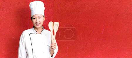 Photo for Young adult pretty asian woman. restaurant chef with a wooden tool - Royalty Free Image