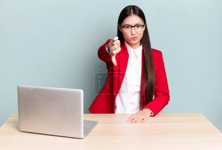 Téléchargez les photos : Pretty asian woman feeling cross,showing thumbs down. business desk concept - en image libre de droit