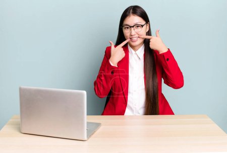 Photo for Pretty asian woman smiling confidently pointing to own broad smile. business desk concept - Royalty Free Image