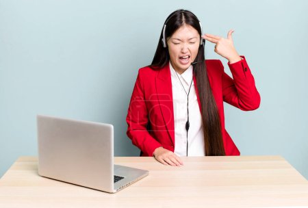 Foto de Mujer asiática bonita mirando infeliz y estresado, gesto suicida haciendo señal de arma. concepto de escritorio de negocios - Imagen libre de derechos