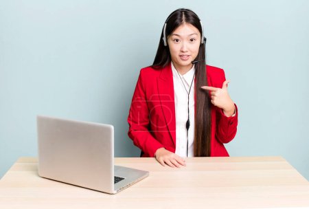 Photo for Pretty asian woman looking shocked and surprised with mouth wide open, pointing to self. business desk concept - Royalty Free Image