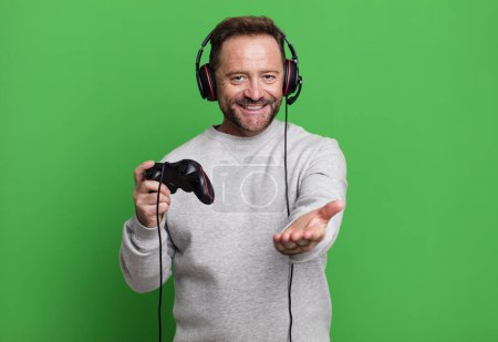 Photo for Middle age man smiling happily with friendly and  offering and showing a concept. gamer concept with a control and headset - Royalty Free Image