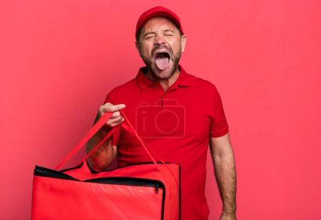Foto de Hombre de mediana edad con actitud alegre y rebelde, bromeando y sacando la lengua. repartidor de pizza - Imagen libre de derechos