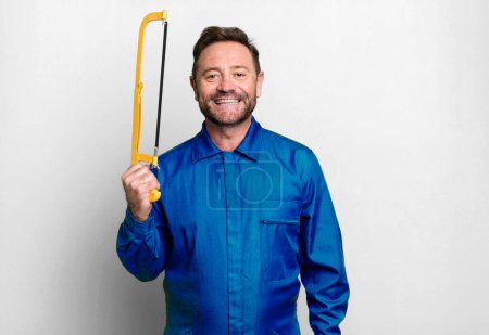 Photo for Middle age repairman with a hand saw sport coach concept with a soccer ball - Royalty Free Image