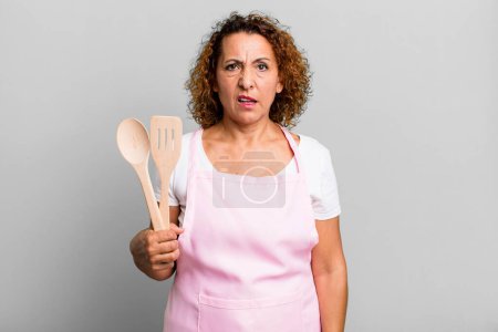Foto de Pretty middle age woman feeling puzzled and confused. home wife chef concept - Imagen libre de derechos