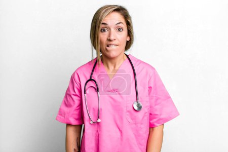 Foto de Mujer rubia bonita buscando desconcertado y confundido. concepto de enfermera - Imagen libre de derechos
