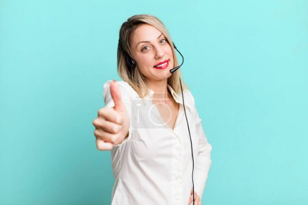 Photo for Pretty blonde woman feeling proud,smiling positively with thumbs up. telemarketer concept - Royalty Free Image