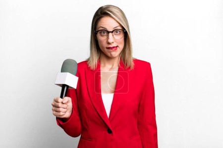 Foto de Pretty blonde woman looking puzzled and confused. presenter or journalist with a microphone - Imagen libre de derechos