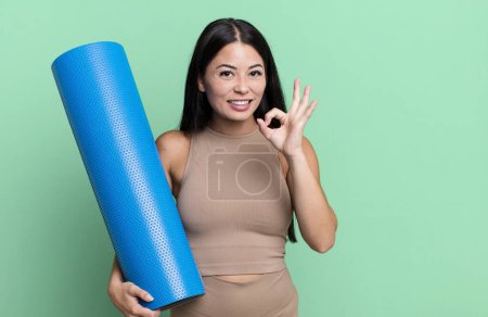 Téléchargez les photos : Hispanique jolie femme se sentant heureuse, montrant l'approbation avec le concept de yoga geste correct - en image libre de droit
